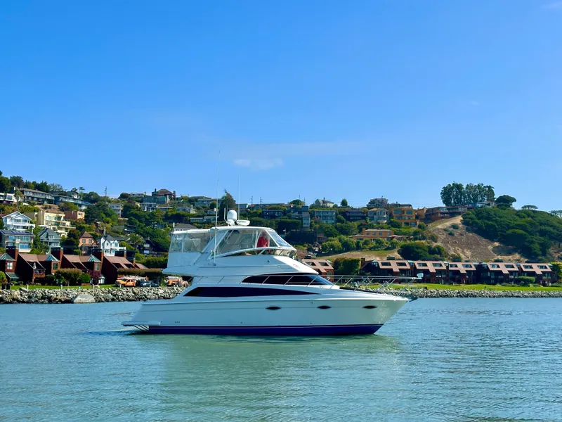 The Image of 2008 Carver 43 Super Sport yacht on calm water with scenic hillside background. - 0