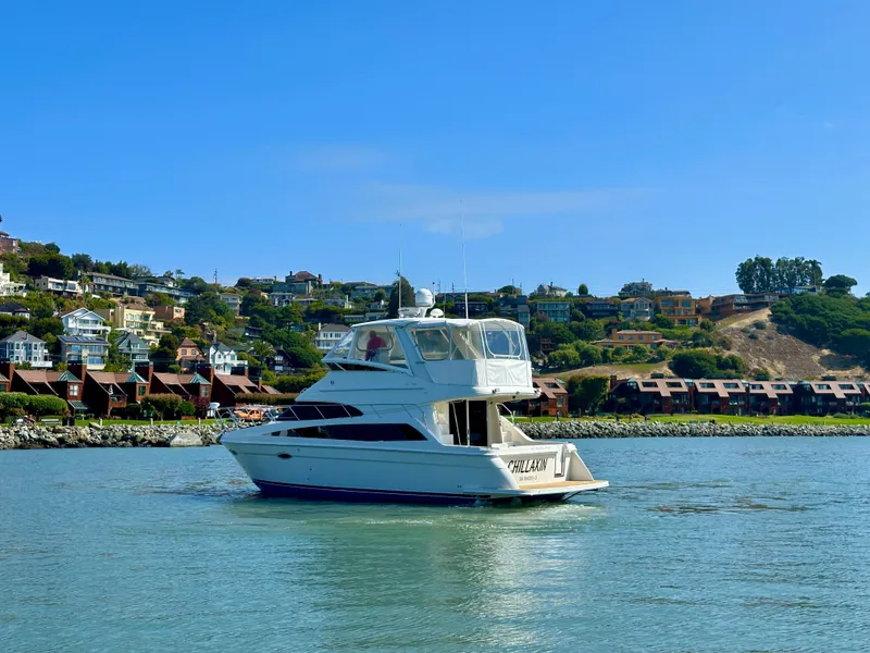 Slide: The Image of 2008 Carver 43 Super Sport yacht cruising near coastal homes under clear blue skies. - 3