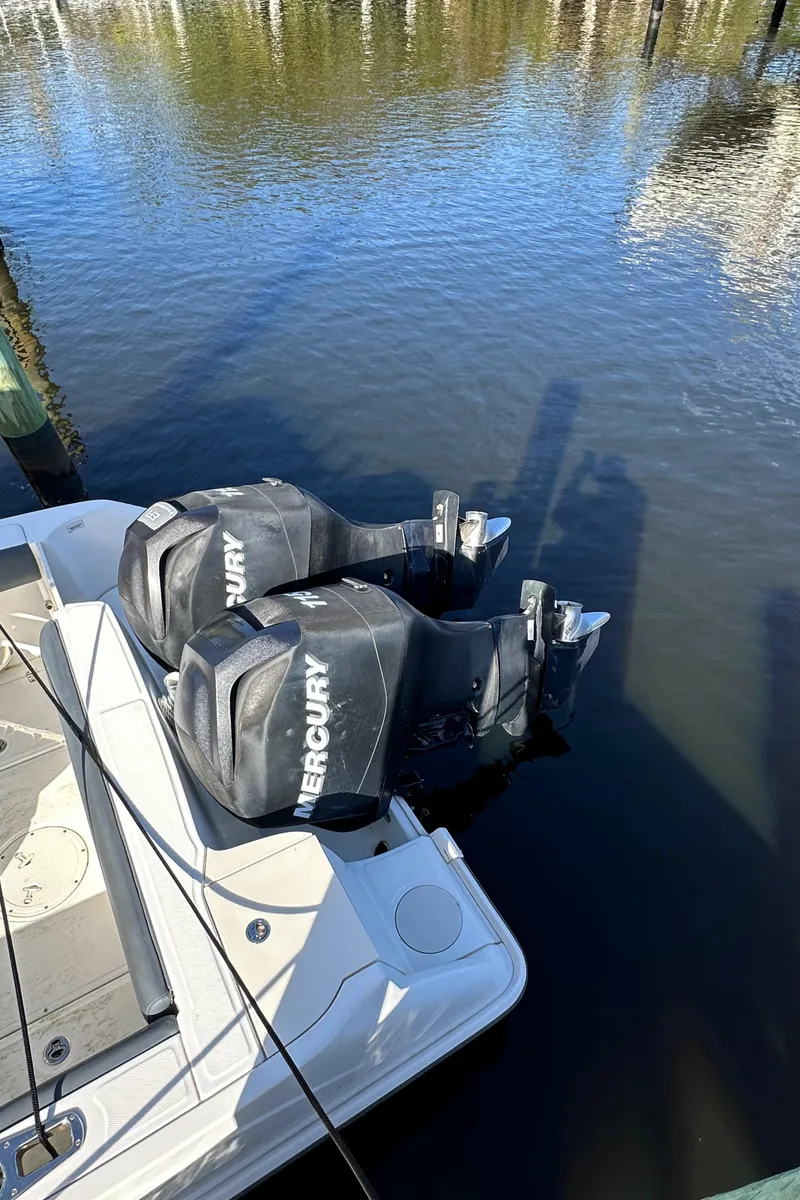 Slide: The Image of 2012 Boston Whaler 220 Outrage with twin Mercury outboard engines docked on calm water. - 7