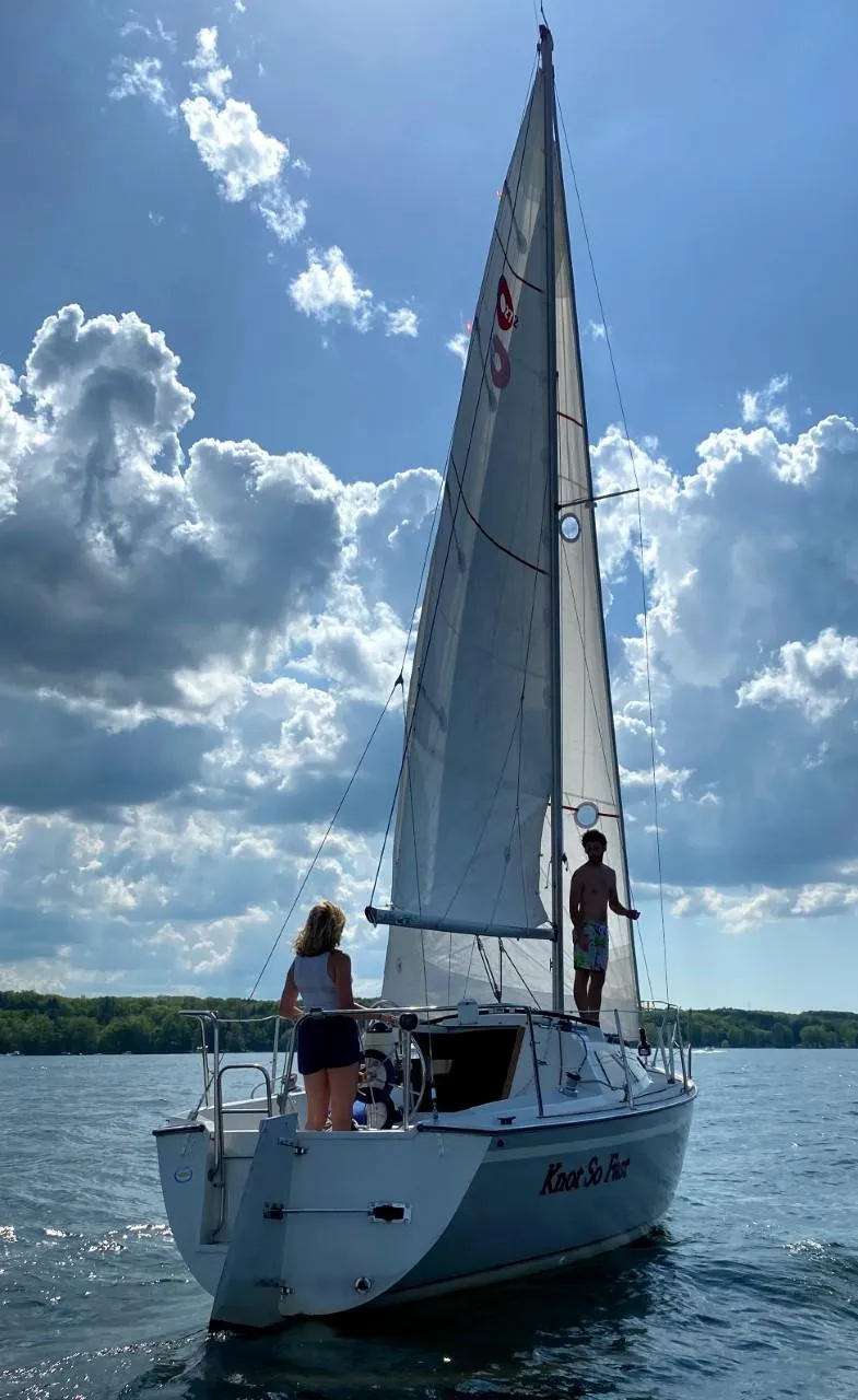 Slide: The Image of 1988 O'Day 27' LE sailboat on water with two people, under a partly cloudy sky. - 5