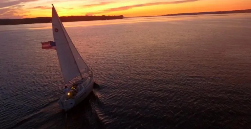 Slide: The Image of Sailboat "1988 O'Day 27' LE" cruising at sunset with American flag on calm waters. - 6