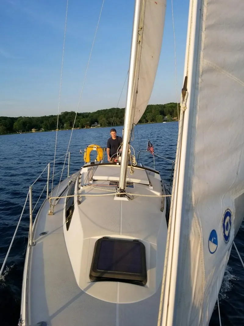 Slide: The Image of 1988 O'Day 27' LE sailboat on a serene lake, clear sky, lush shoreline. - 8