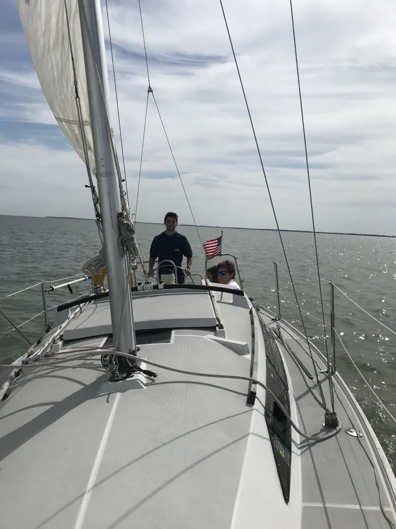 Slide: The Image of 1988 O'Day 27' LE sailboat on open water with two people onboard. - 9