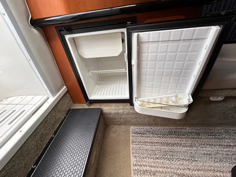Slide: The Image of 2007 Crownline 255 CCR boat interior with open mini fridge and carpeted floor. - 44