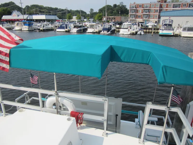 Slide: The Image of 1995 Gibson 44 Classic boat with teal canopy docked at marina. - 10