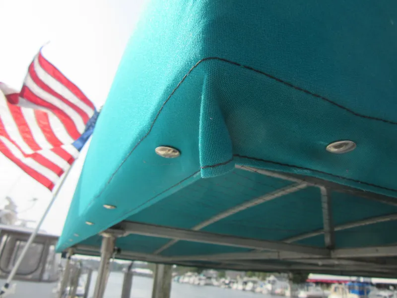 Slide: The Image of Teal boat canopy on 1995 Gibson 44 Classic with American flag in background. - 11