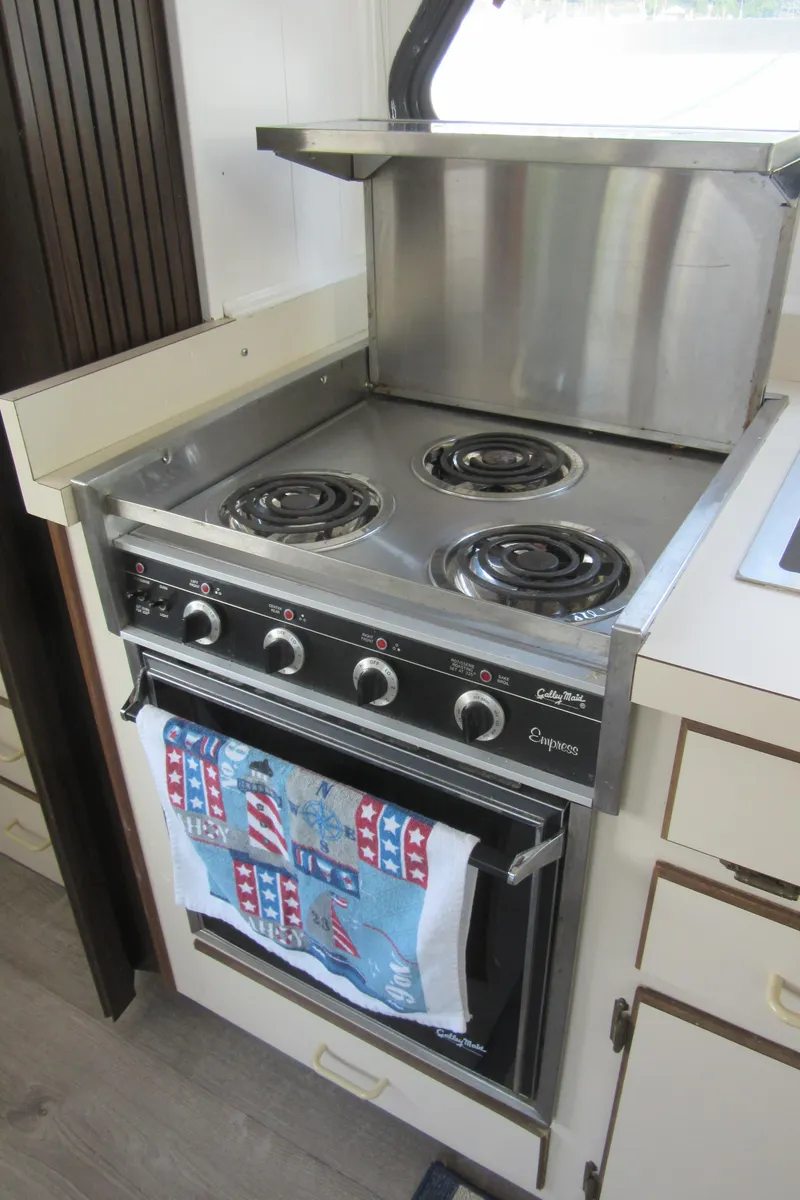 Slide: The Image of 1995 Gibson 44 Classic stove with three burners and oven, featuring a colorful towel. - 42