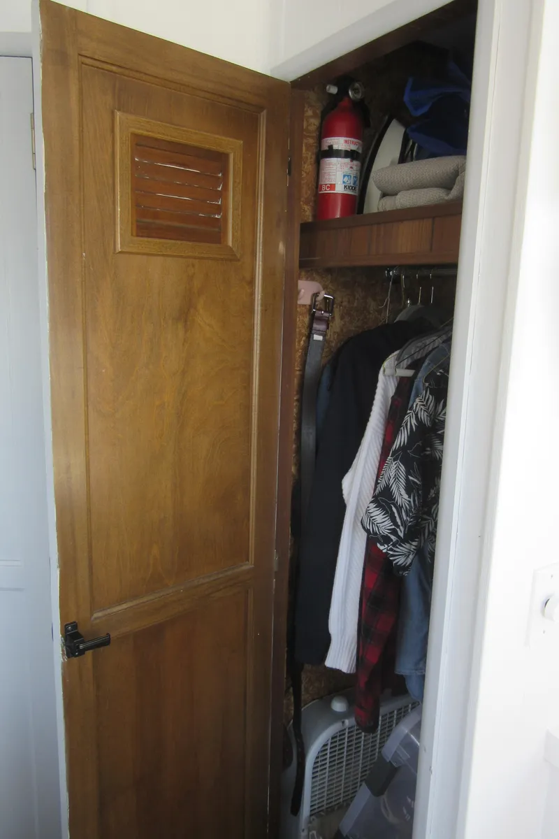 Slide: The Image of Closet with clothes, fire extinguisher, and miscellaneous items on shelves. - 47