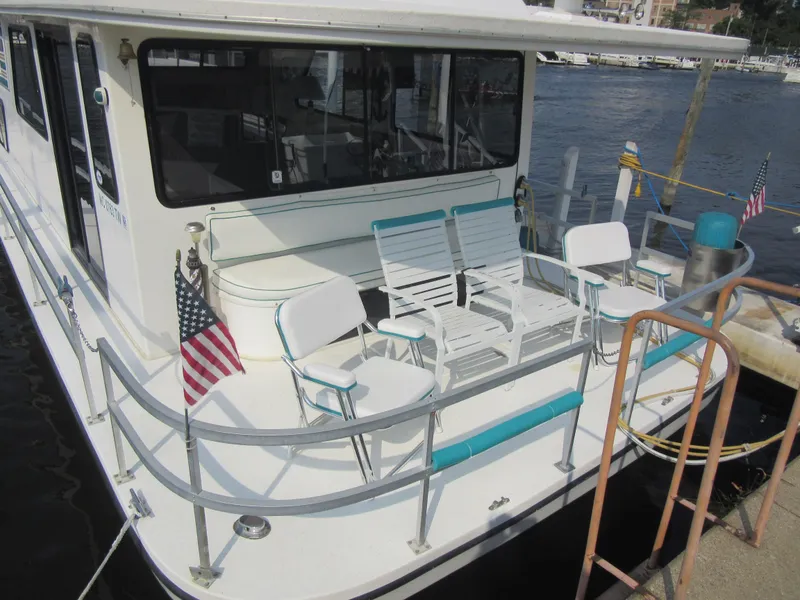 Slide: The Image of Gibson 44 Classic houseboat, 1995 model, docked with patio chairs and American flag. - 5