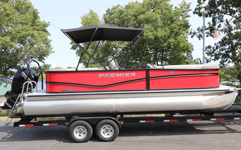 The Image of 2025 Premier 220 Sunscape pontoon boat on trailer, red and silver design, parked outdoors. - 1