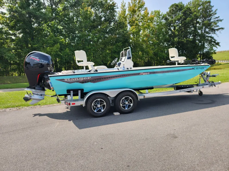 Slide: The Image of 2022 Ranger RB200 boat on trailer, parked outdoors, with trees in the background. - 1