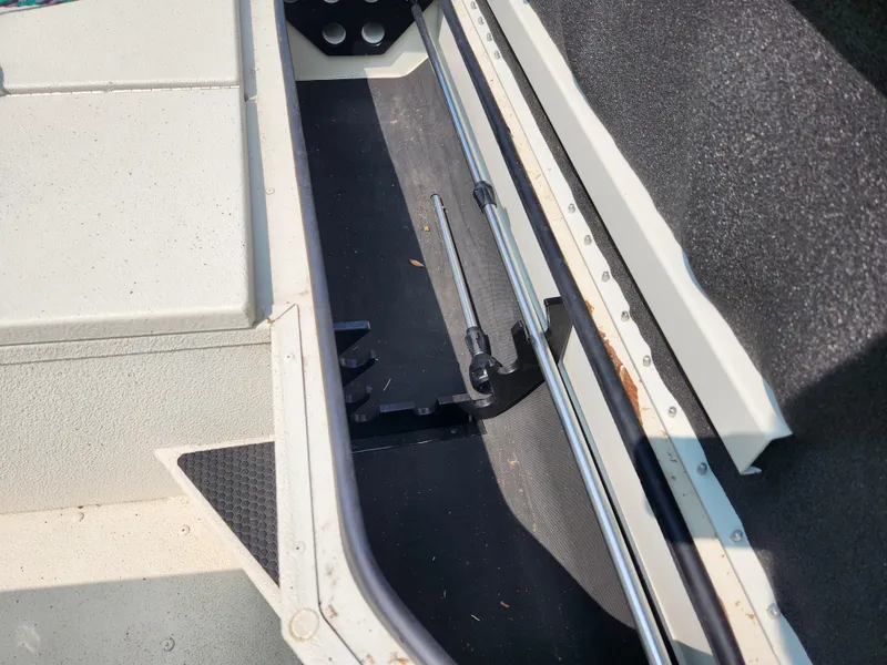 Slide: The Image of 2022 Ranger RB200 boat storage compartment with rod holders and carpeted interior. - 8