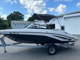 Slide: The Image of 2019 Yamaha SX195 boat on trailer, parked outdoors under blue sky. - 0