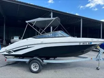 Slide: The Image of 2019 Yamaha SX195 boat on trailer under canopy, side view. - 1