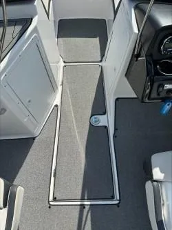 Slide: The Image of 2019 Yamaha Boats SX195 interior with gray carpet and sleek dashboard design. - 14