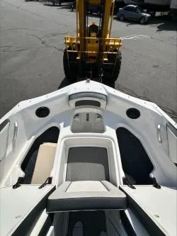 Slide: The Image of 2019 Yamaha Boats SX195, white interior, parked near a forklift on asphalt. - 23