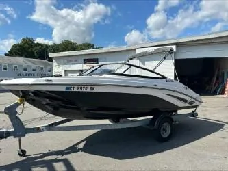 Slide: The Image of 2019 Yamaha Boats SX195 on trailer, parked outside a marine store under a blue sky. - 4