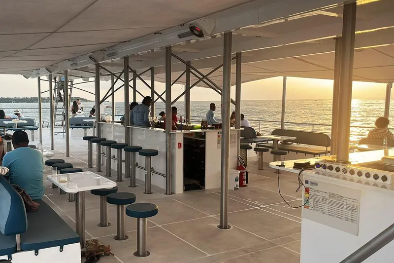 Slide: The Image of Modern PaxCat 80 boat interior with bar and seating, sunset view over the ocean, 2024 model. - 10