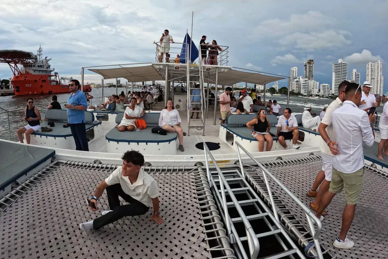 Slide: The Image of People relaxing on a Custom PaxCat 80 catamaran, 2024, with city skyline in background. - 7