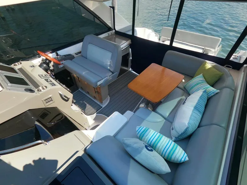 Slide: The Image of Interior of 2011 Regal 42 Sport Coupe with seating and helm, featuring colorful cushions. - 19