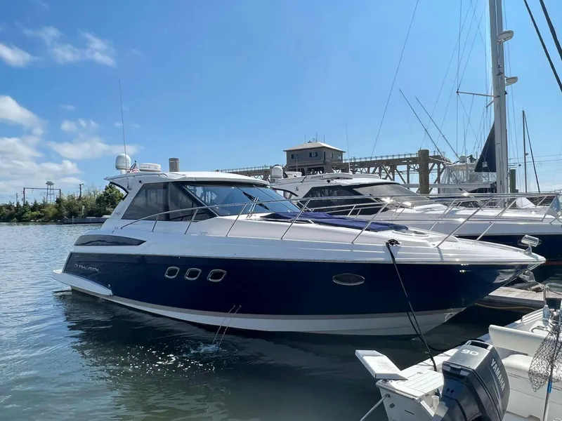 Slide: The Image of 2011 Regal 42 Sport Coupe yacht docked in a marina under a clear blue sky. - 5