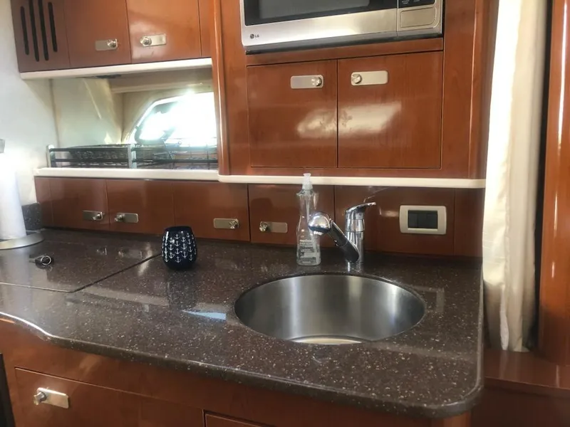 Slide: The Image of 2012 Sea Ray 350 Sundancer yacht kitchen with sink, microwave, and wooden cabinetry. - 7