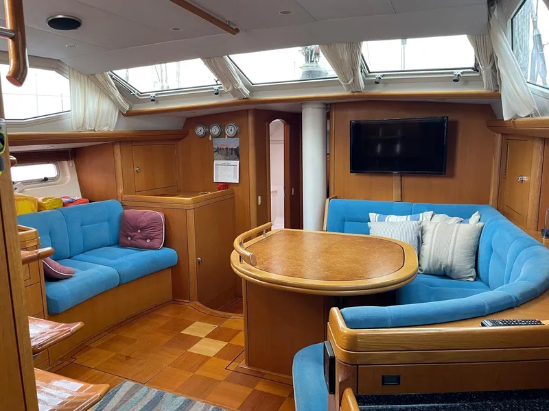 Slide: The Image of Luxurious 2003 Oyster 53 yacht interior with blue seating, wooden table, and modern amenities. - 10