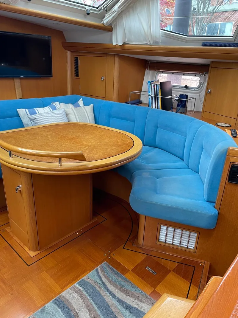Slide: The Image of Interior of 2003 Oyster 53 yacht with blue seating and wooden table. - 18