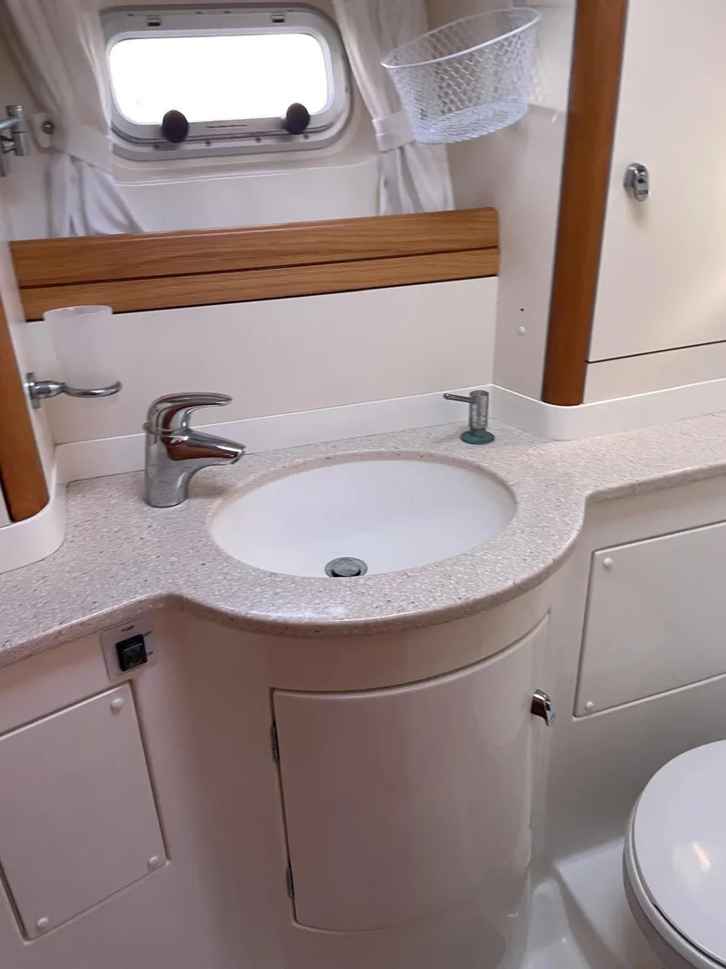 Slide: The Image of 2003 Oyster 53 yacht bathroom with sink, faucet, and porthole window. - 37