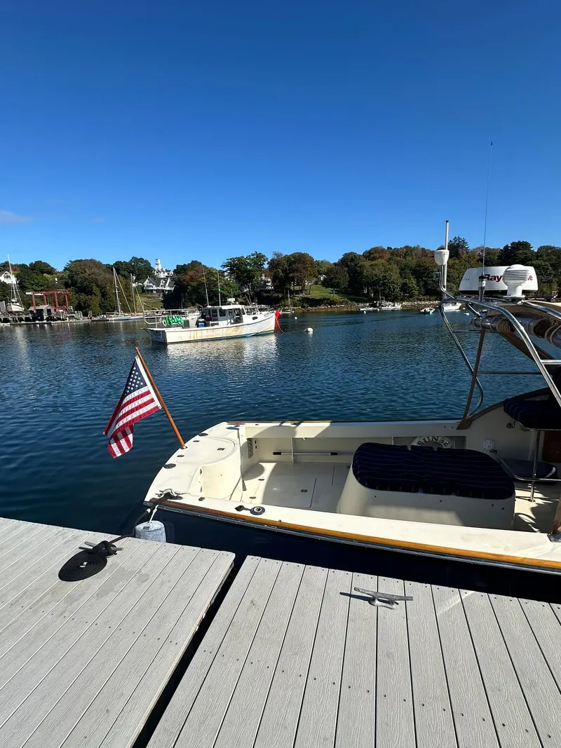 Slide: The Image of Hinckley T29 Express 1997 docked by a serene waterfront with American flag. - 16
