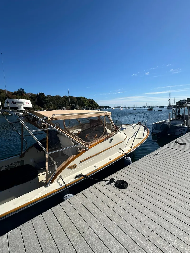 Slide: The Image of 1997 Hinckley T29 Express docked by a serene waterfront under a clear blue sky. - 19