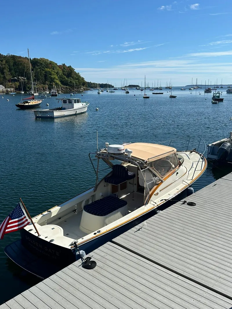 Slide: The Image of 1997 Hinckley T29 Express docked in a scenic marina with calm waters and sailboats. - 20
