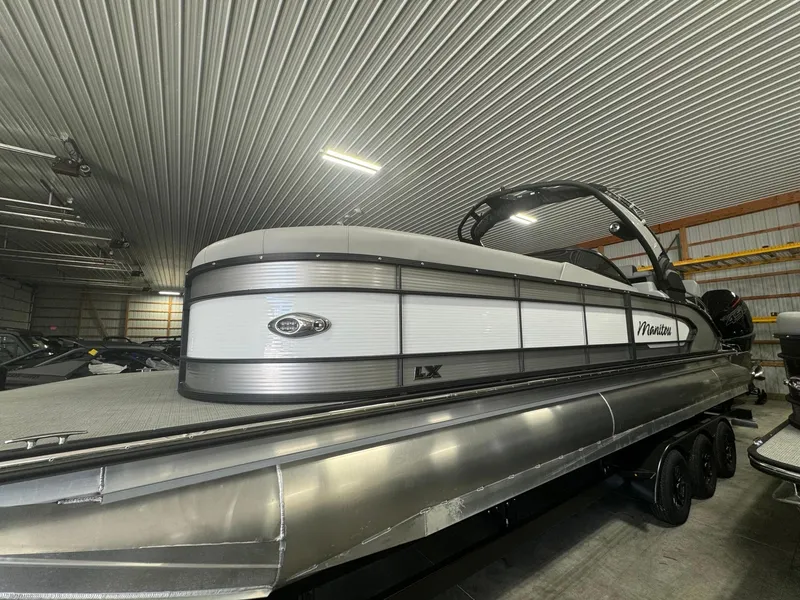 The Image of 2025 Manitou LX pontoon boat in a storage facility. - 0