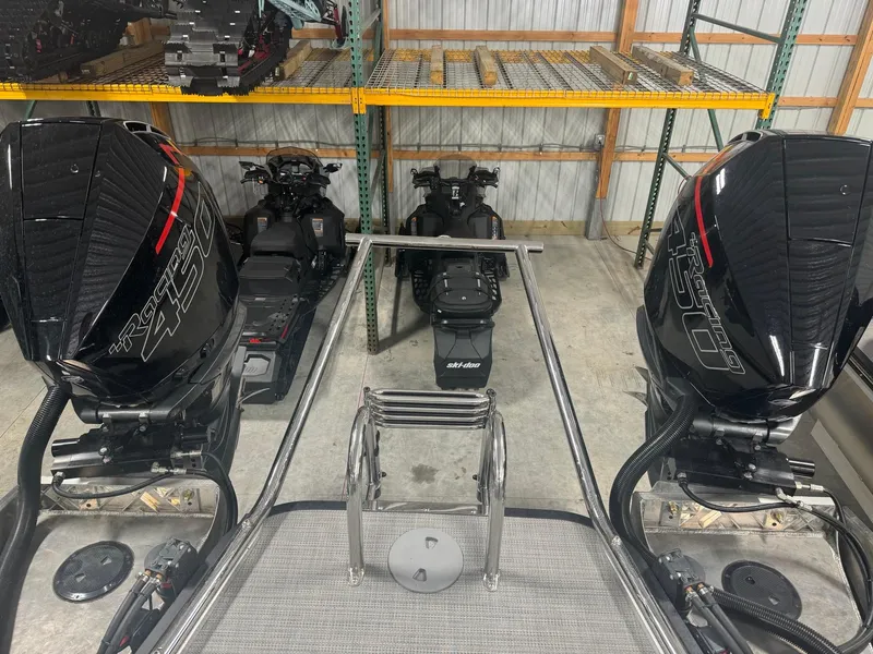 Slide: The Image of 2025 Manitou LX boat with dual outboard motors in a storage facility. - 16