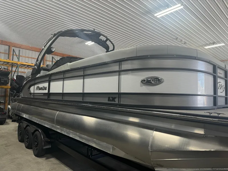 Slide: The Image of 2025 Manitou LX pontoon boat in a storage facility. - 23