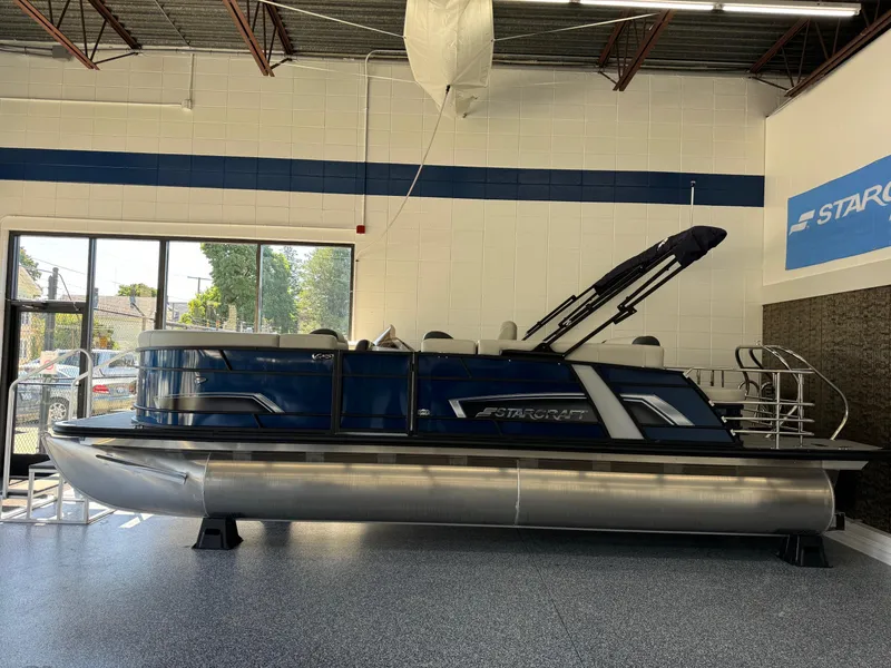 Slide: The Image of 2025 Starcraft EXS 3 Q pontoon boat displayed indoors. - 1