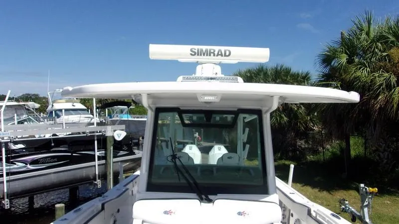 Slide: The Image of 2022 Crevalle 33 CSF Offshore Fishing boat with Simrad radar, docked near palm trees. - 16