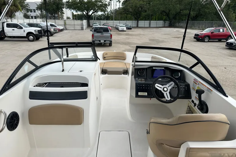 Slide: The Image of 2023 Bayliner VR4 Bowrider OB interior with steering wheel and seating in a parking lot. - 4