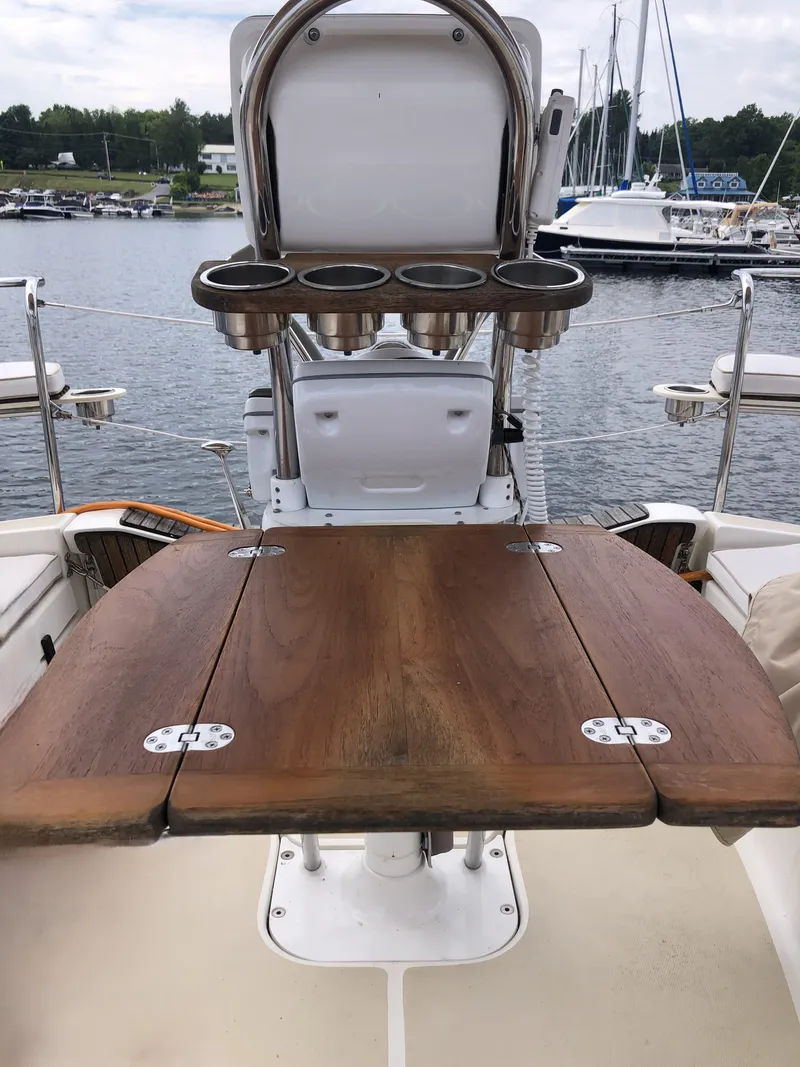 Slide: The Image of 2016 Marlow-Hunter 37 sailboat cockpit with wooden table and cup holders, docked at marina. - 49
