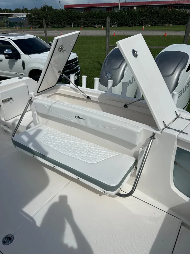 Slide: The Image of 2022 Stamas 33T Aventura boat with open storage compartments and dual Suzuki outboard motors. - 7