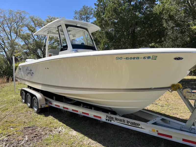 Slide: The Image of 2023 Pursuit S 288 boat on trailer, parked outdoors with trees in background. - 1