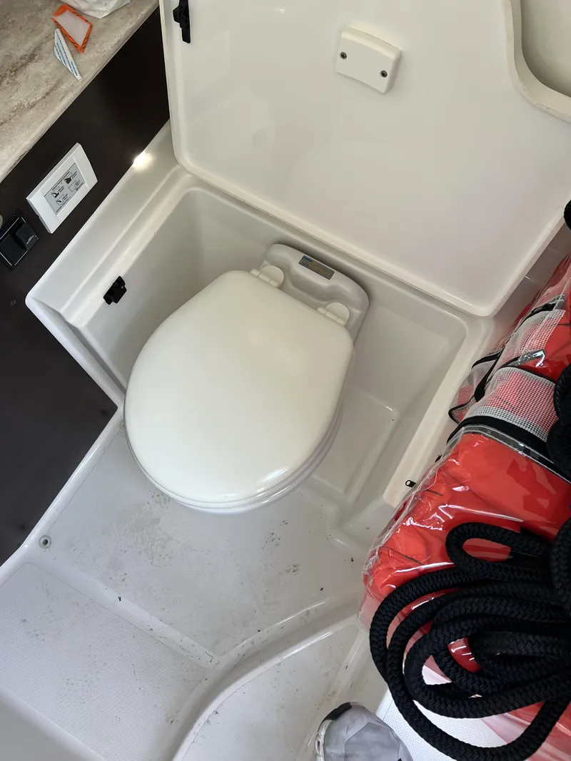 Slide: The Image of 2023 Pursuit S 288 boat interior with compact marine toilet and safety equipment. - 18