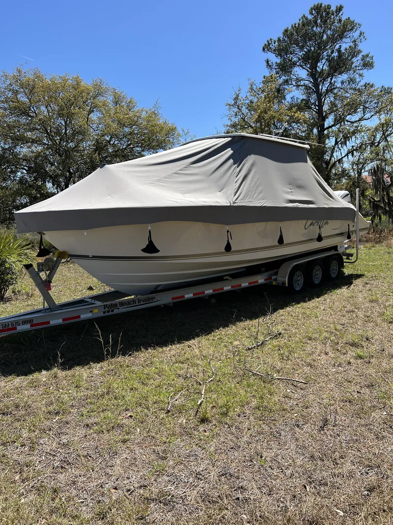 Slide: The Image of 2023 Pursuit S 288 boat covered on trailer in grassy area. - 24
