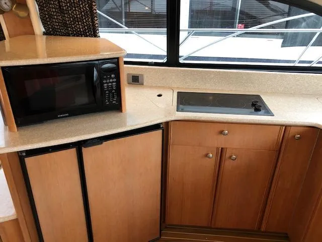 Slide: The Image of 2003 Meridian 411 yacht kitchen with microwave, stove, and wooden cabinets. - 12