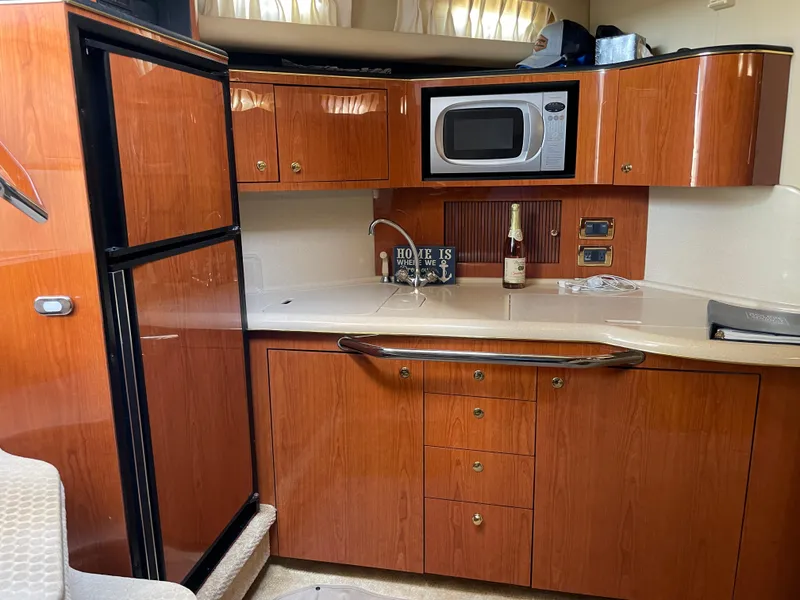 Slide: The Image of 2001 Sea Ray 380 Sundancer yacht kitchen with wood cabinets, microwave, and fridge. - 17