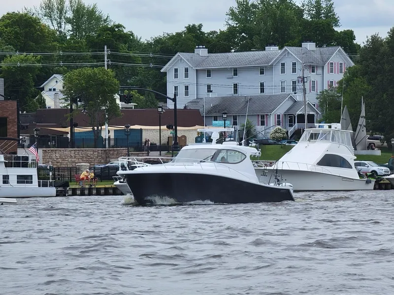 Slide: The Image of 2021 Jupiter 41 SB boat on a calm lake with lush green shoreline. - 0
