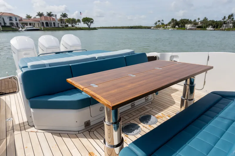 Slide: The Image of The image shows the deck of a 2025 SACS Rebel 47 with blue seating and a wooden table. - 24