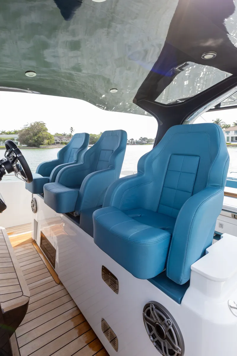 Slide: The Image of Three blue captain's chairs on a modern boat with wooden flooring and a view of the water. - 29