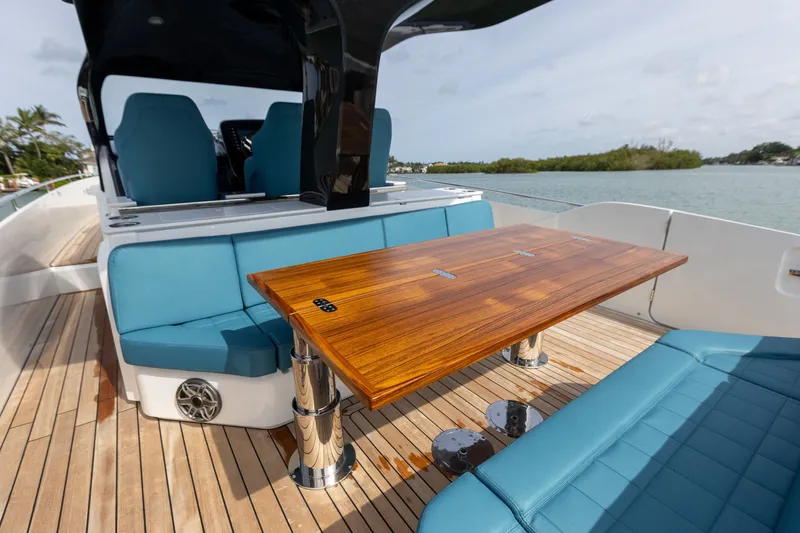 Slide: The Image of The image shows the deck of a 2025 SACS Rebel 47 with blue seating and a wooden table. - 23