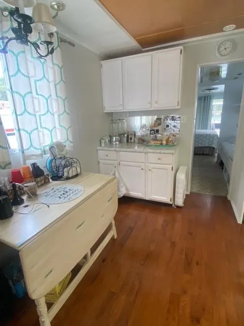 Slide: The Image of Interior of 1985 Arc houseboat with wooden floors, white cabinets, and decorative curtains. - 11